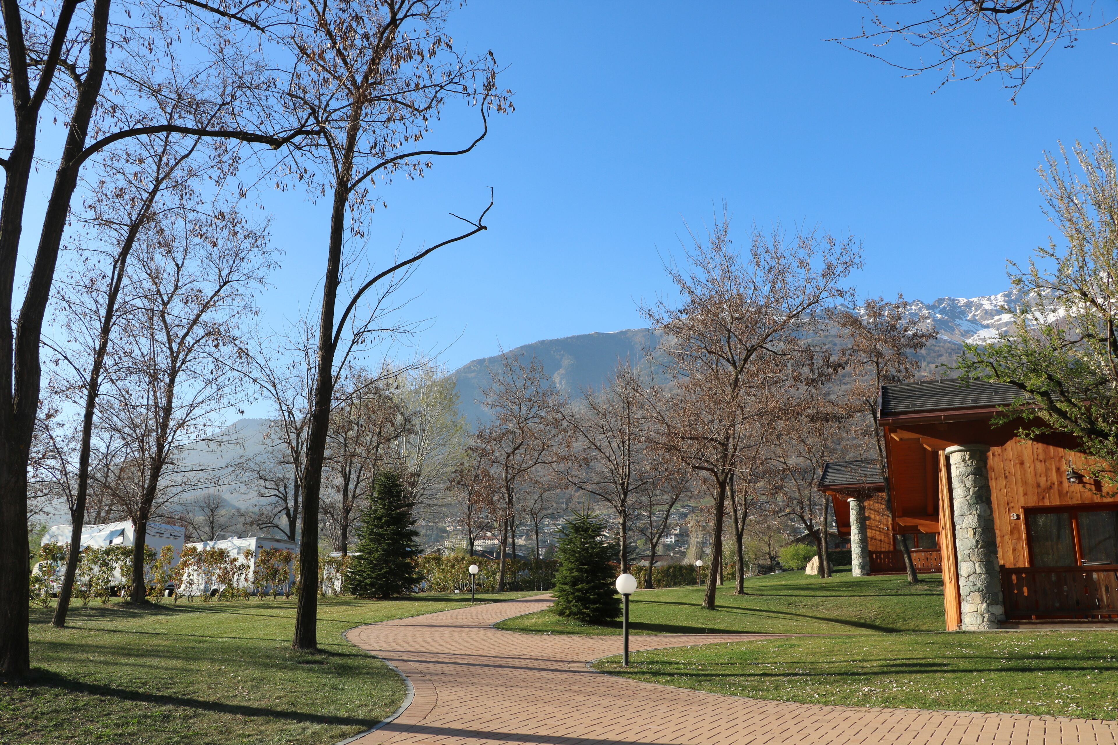 Ein Weg führt zu einer Lodge mit Steinsäulen und einem Berg im Hintergrund.