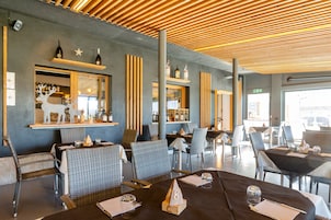 Un restaurante con sillas y mesas de mimbre, una zona de bar con botellas y un techo de madera.