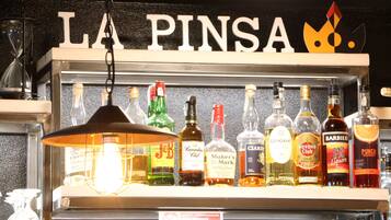 A bar shelf with various liquor bottles and a sign above reading "LA PINSA".