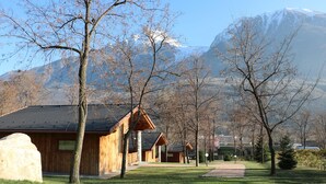 A row of wooden cabins with a mountain backdrop. - Lazy Bee Camping Village (Quart)