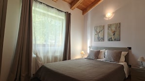A bedroom with a bed, curtains, two wall-mounted lamps, and two paintings. - Lazy Bee Camping Village (Quart)