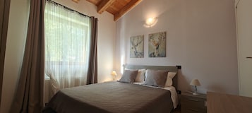 Un dormitorio con cama, cortinas, dos lámparas de pared y dos cuadros.