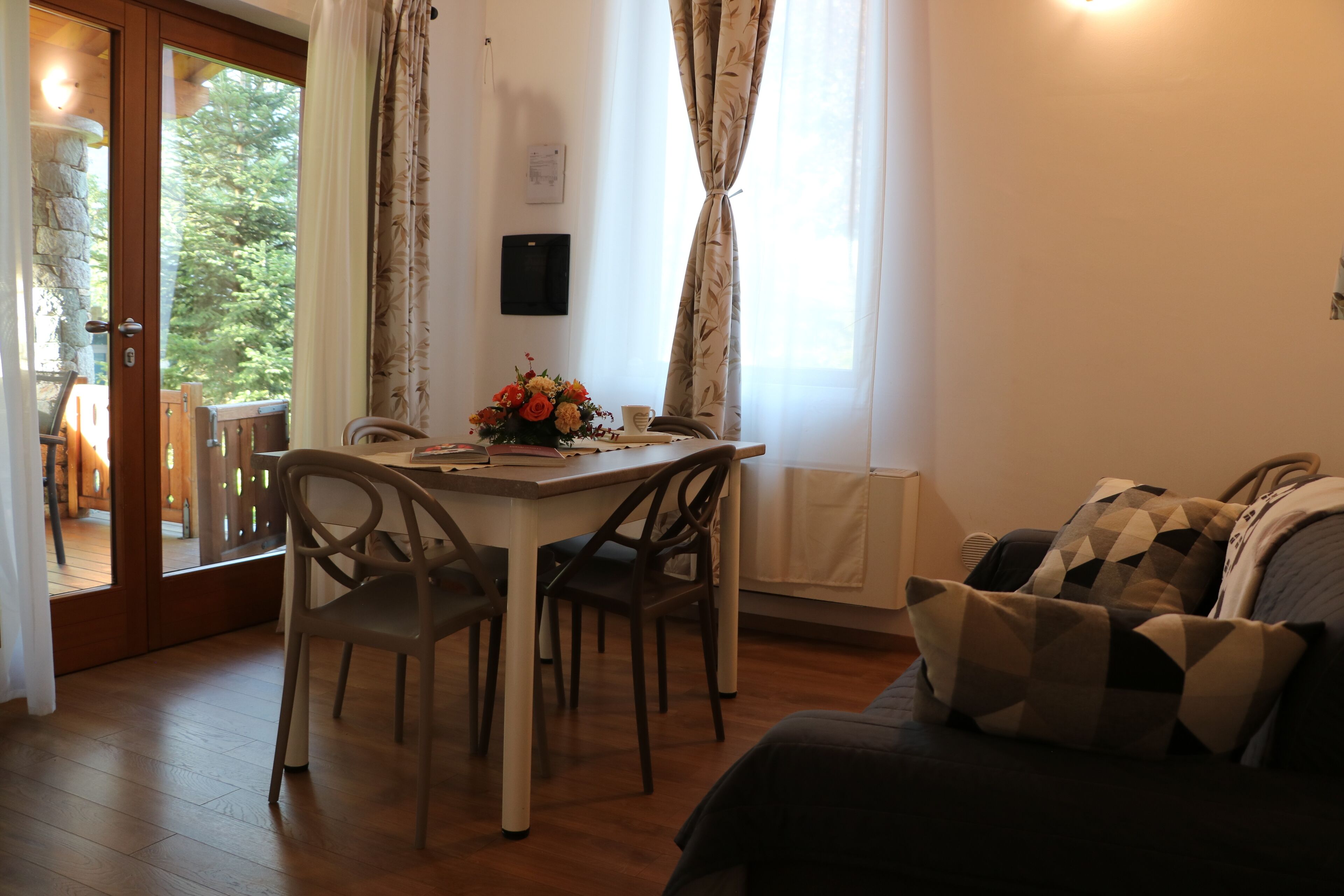 A cozy room with a dining table, chairs, a sofa, and a view of the outdoors.