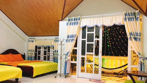 A room with two beds, a seating area, and a view of the outside. - Pensee Guesthouse (Lam Vien - Da Lat)