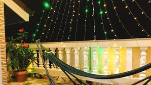A hammock on a balcony with string lights and potted plants. - Pensee Guesthouse (Lam Vien - Da Lat)