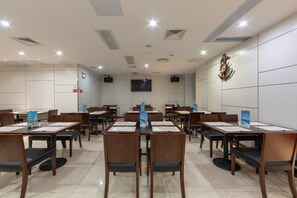 Una sala de conferències amb diverses taules i cadires, equipada amb matissos i una pantalla de televisió.