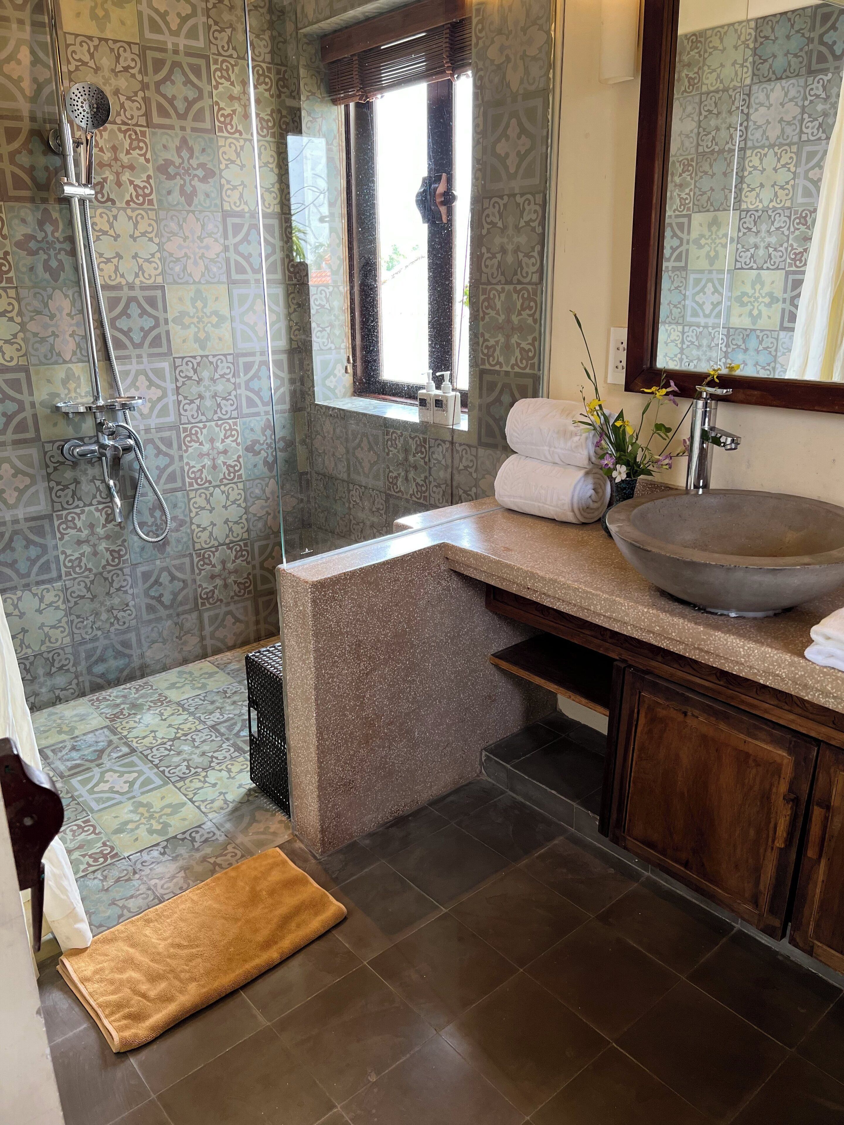 Une salle de bain avec une douche, un lavabo, une fenêtre et un miroir.
