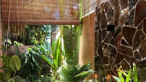 A stone pathway leading to a large, curved bathtub, surrounded by lush tropical plants and a bamboo structure. - An Villa Hoi An (Da Nang)