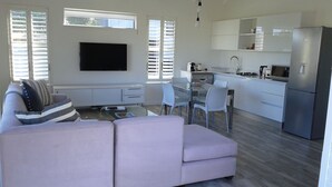 Un salon moderne comprenant un canapé, un téléviseur à écran plat et un coin repas avec des chaises et une table.