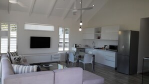 Un salon moderne avec un canapé, une table basse en verre et un téléviseur à écran plat fixé au mur.