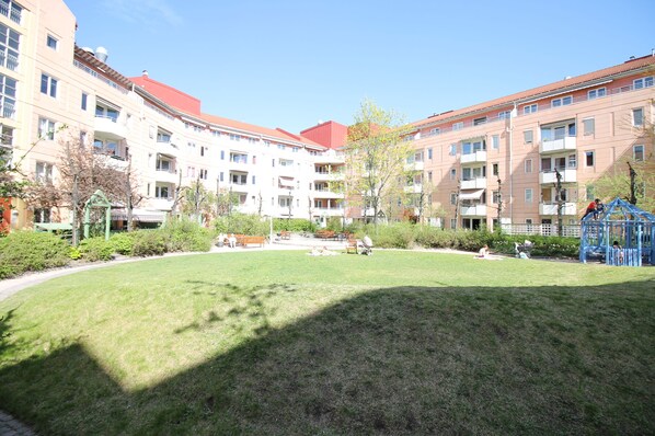 A courtyard with a grassy lawn, benches, and a playground. - Apartment P1 Oslo City (Oslo)