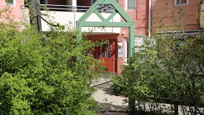 Une entrée d’immeuble avec une arche verte, une porte rouge et une plaque portant le numéro 23.
