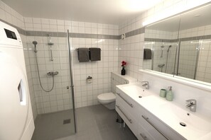 A modern bathroom with a shower, toilet, and sink.