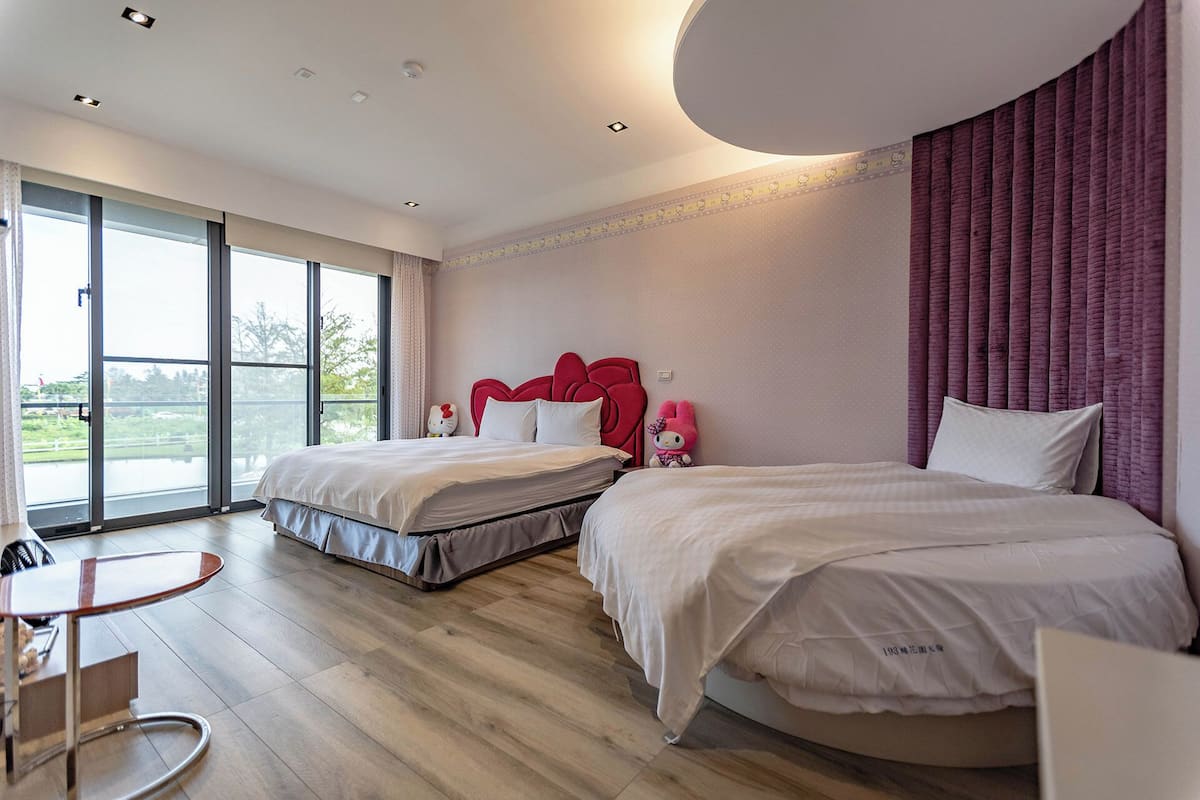 Habitación de hotel con dos camas, un ventanal grande y un balcón.