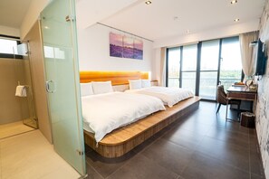 A modern hotel room with a large bed, a desk, and a view of the outdoors.