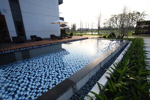 A swimming pool with a tiled edge, lounge chairs, and umbrellas. - 193 County Garden BnB (Ji'an)