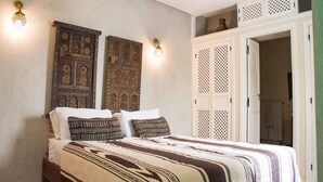 A bedroom with a bed, two wall-mounted lamps, and a wardrobe with a lattice design. - Riad el Marah (Marrakech)