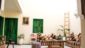 A cozy courtyard with a wooden bench, striped sofas, and a ladder. - Riad el Marah (Marrakech)