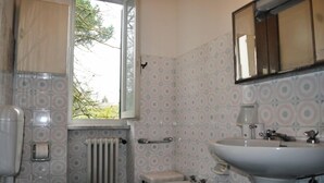 Casa de banho com sanita, bidé e lavatório, tudo em branco.