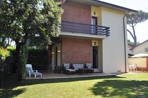 A two-story building with a balcony, outdoor seating area, and a well-maintained lawn. - Villa Fiumetto (Pietrasanta)