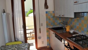 A compact kitchen with a gas stove, a sink, and a tiled backsplash. - Villa Fiumetto (Pietrasanta)