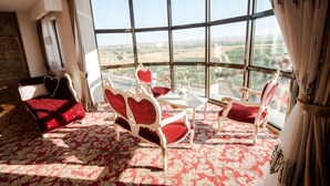 Una habitación con un ventanal grande, una alfombra roja con estampado y una silla blanca y roja con respaldo en forma de corazón.