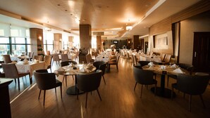 Un restaurante espacioso con varias mesas y sillas, ventanas amplias y una decoración de diseño moderno.