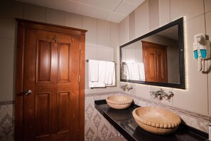 A bathroom with wooden doors, two sinks, a large mirror, and a hairdryer on the wall. - Grand Hotel & Convention Center Karaman (Karaman)