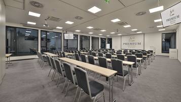 A conference room with multiple tables and chairs, large windows, and a sign reading "Premium Hotel".