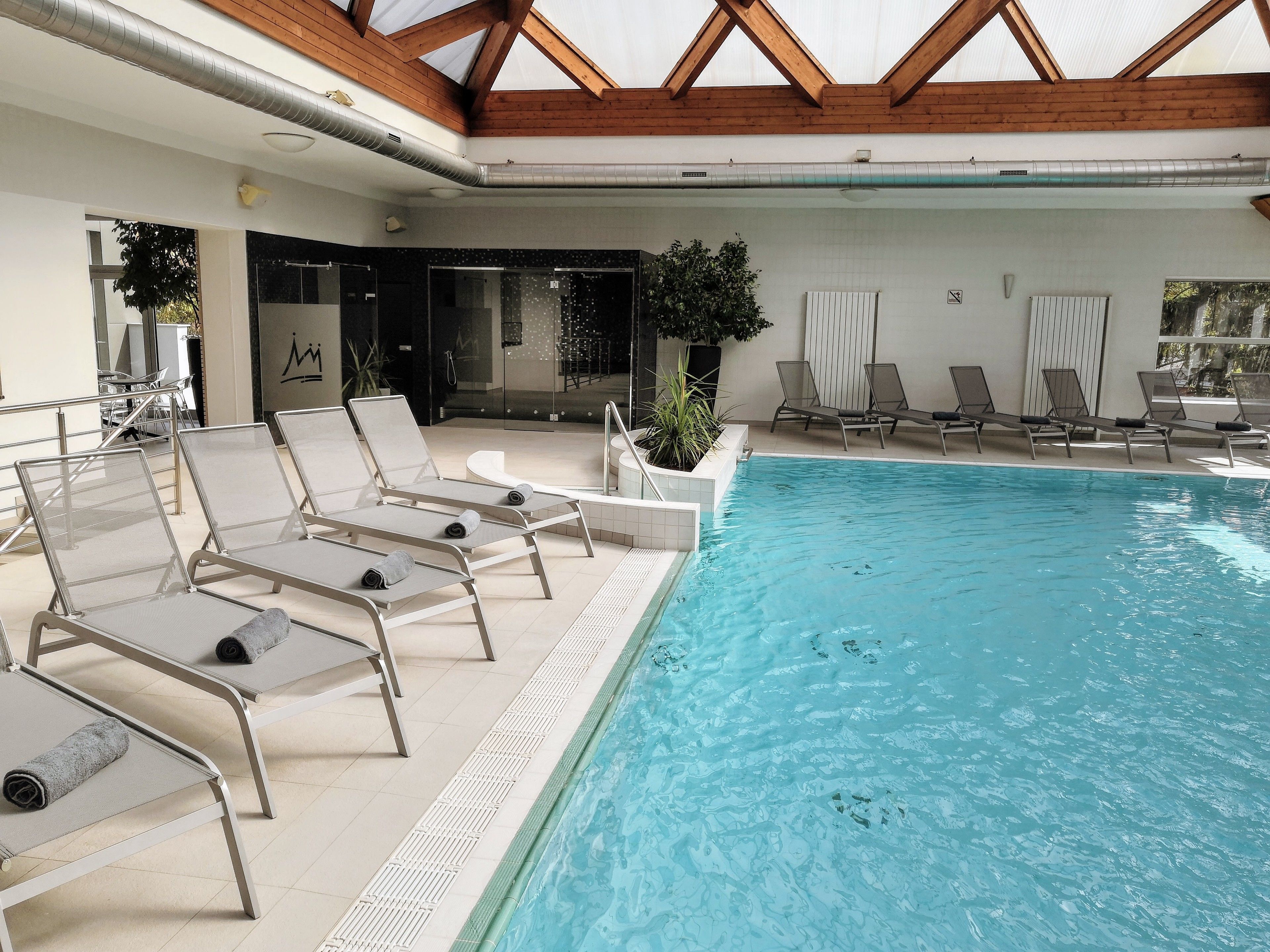 Una piscina interior con sillones de descanso y una estructura de techo de madera.