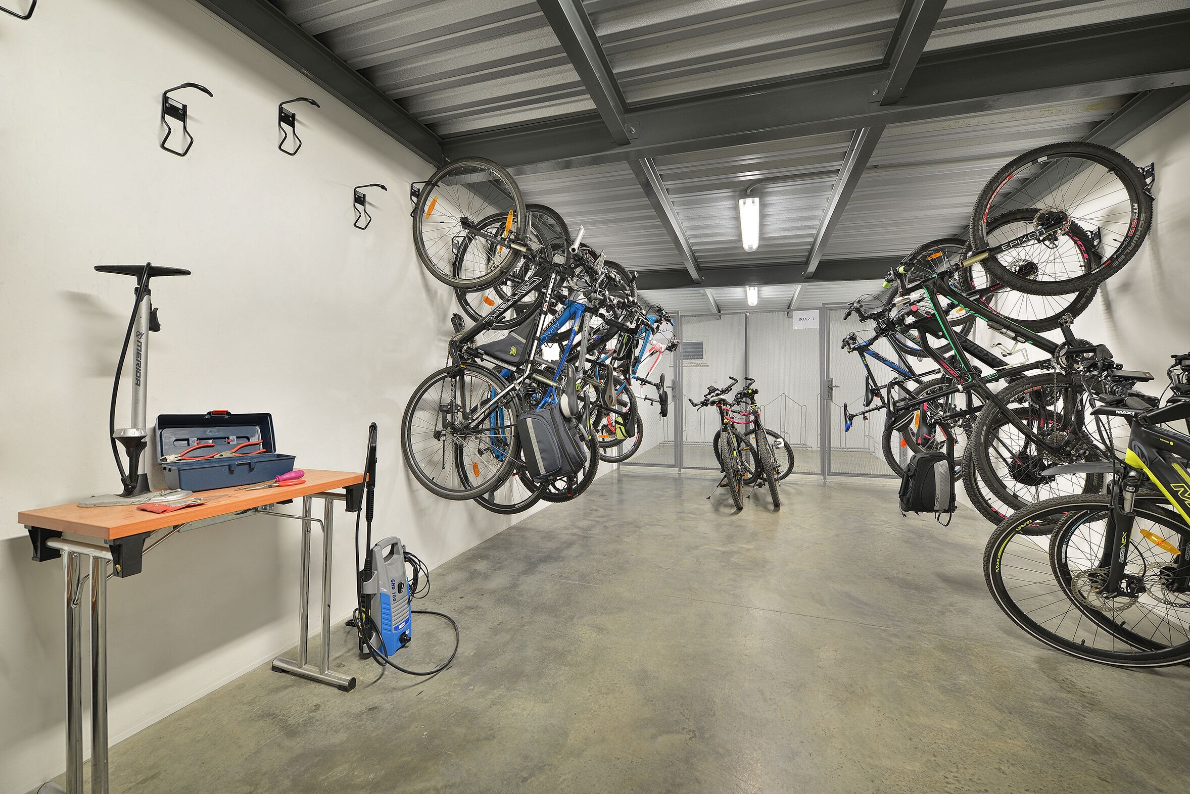 A bike storage area with multiple bicycles and a table with tools.