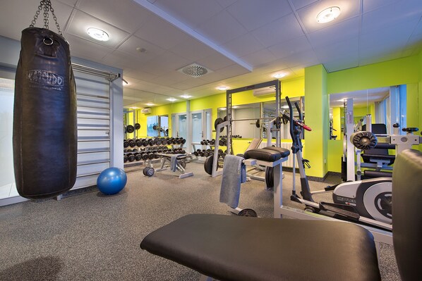 A gym with exercise equipment, a punching bag, and a bench. - PREMIUM Wellness & Wine Hotel (Znojmo)