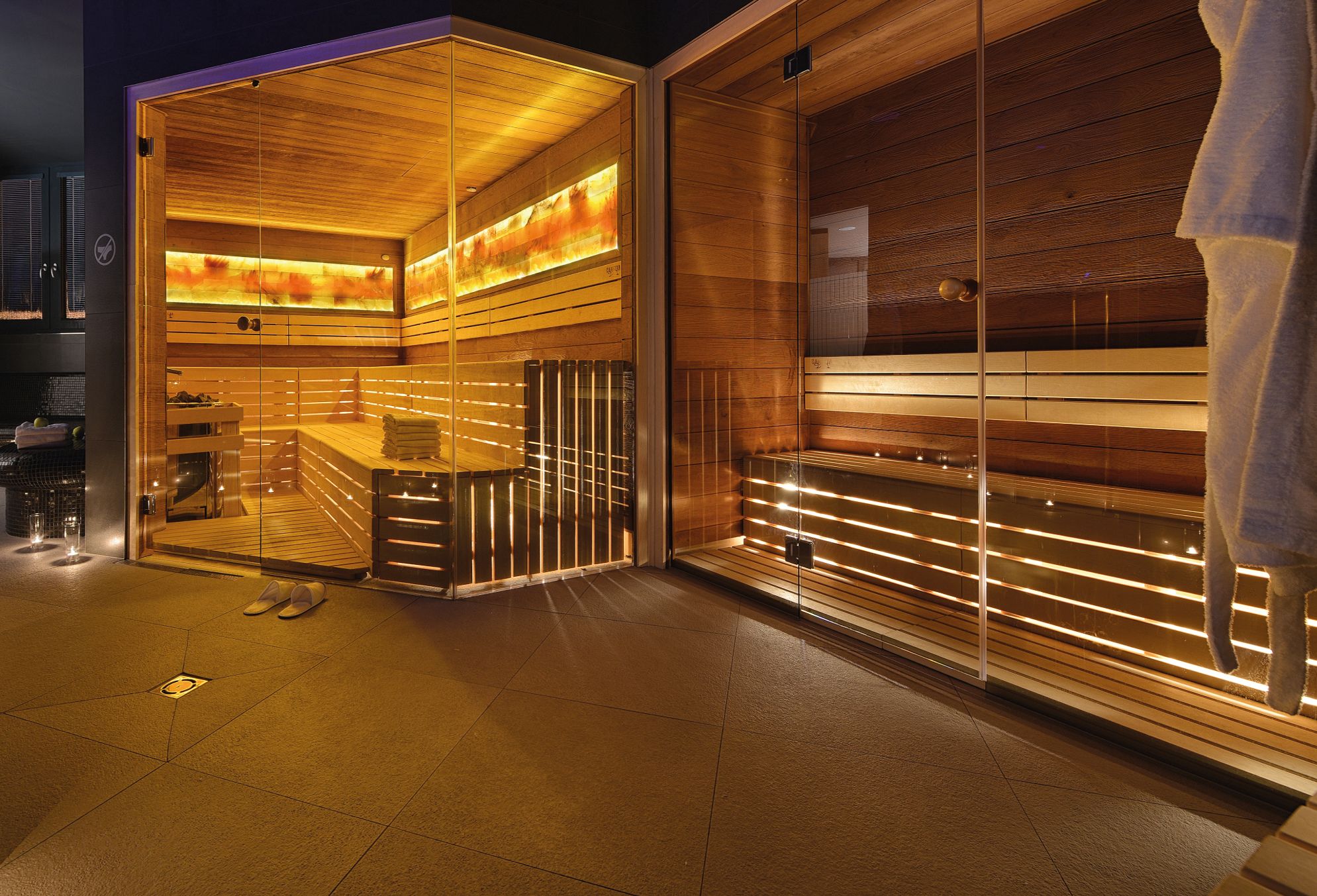 A sauna with wooden walls and a glass door, a bench, and a towel rack.