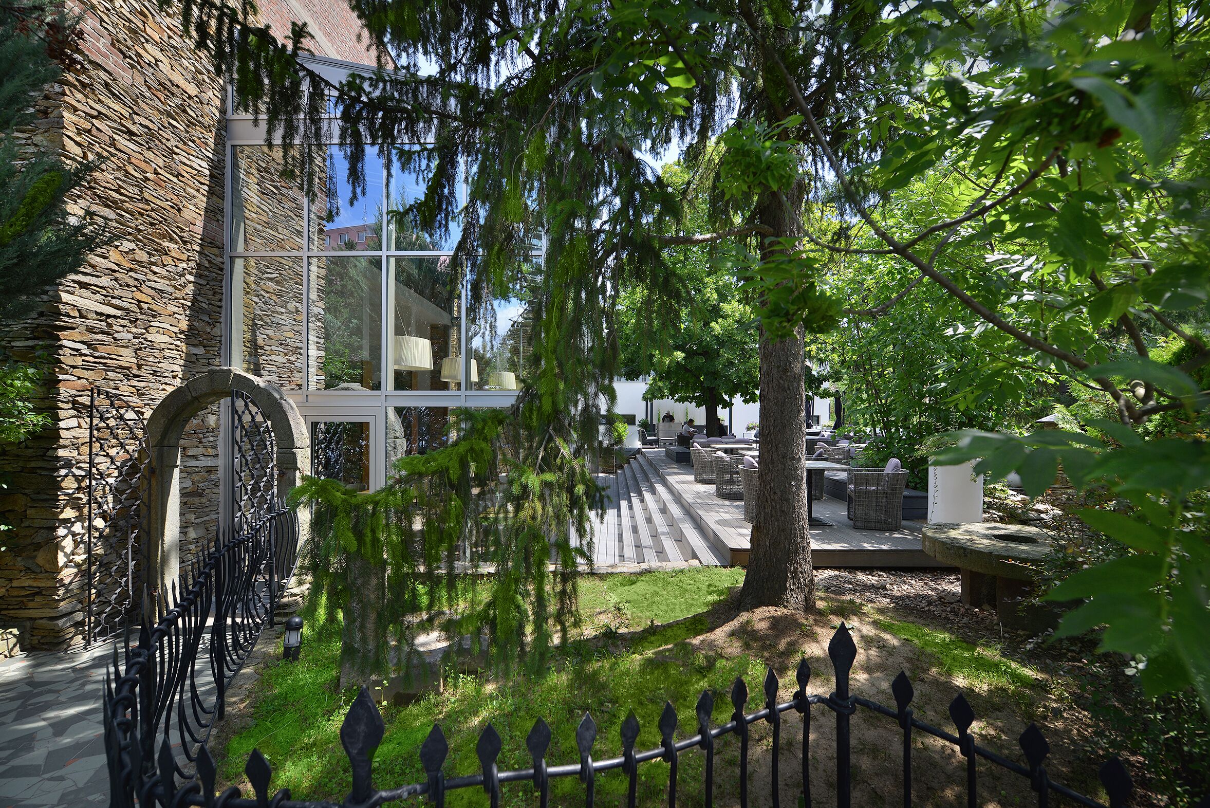 A stone building with a glass facade, outdoor seating area, and a stone pathway.