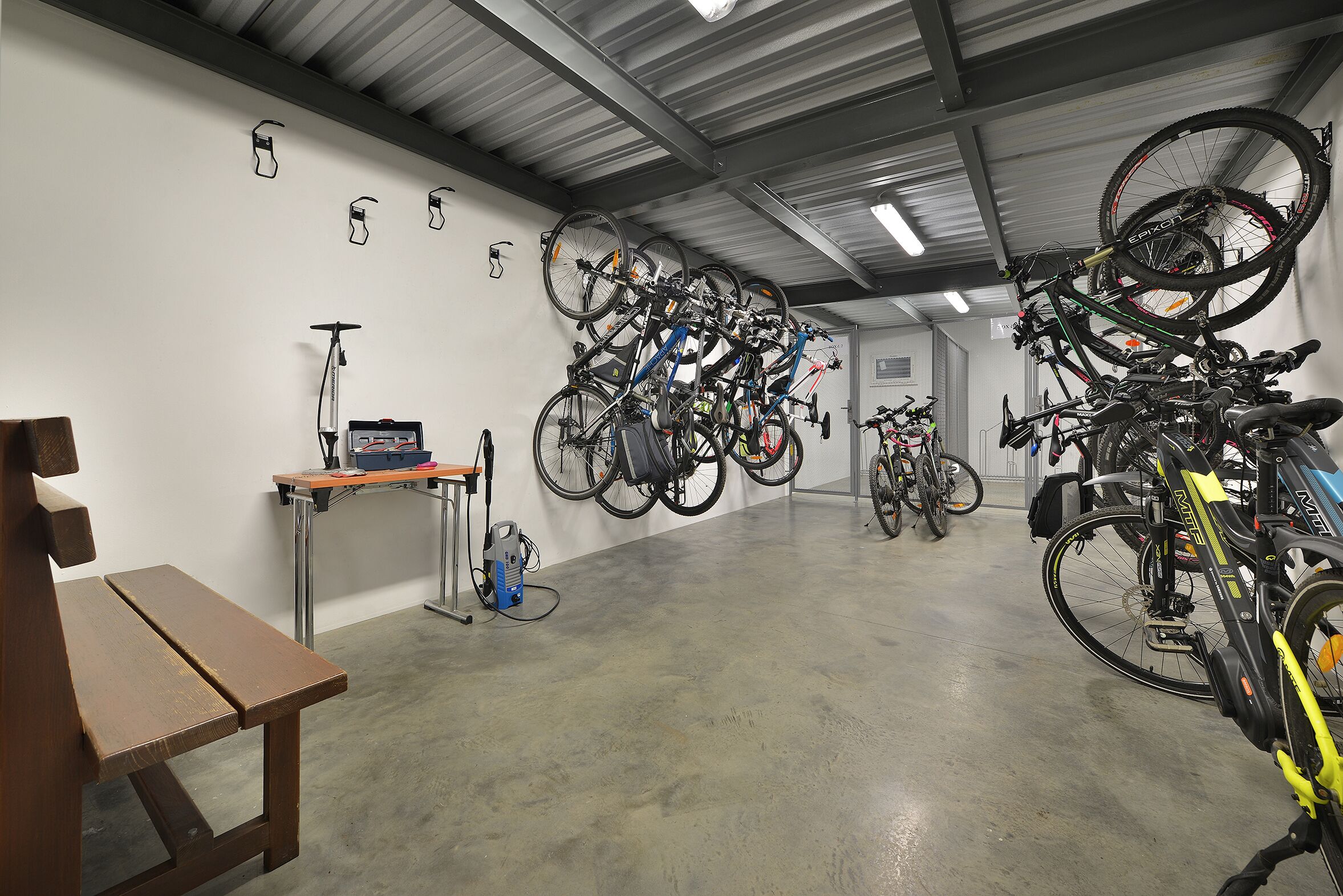 A bicycle storage area with multiple bikes and a scooter rack.