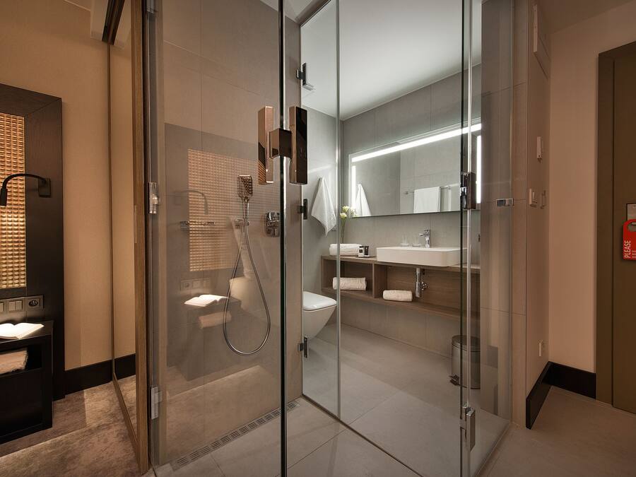 A modern bathroom with a glass-enclosed shower, a toilet, and a sink with a mirror above it.