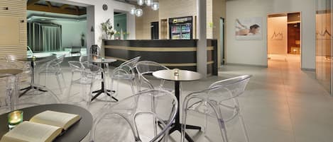 En modern hotellobby med genomskinliga stolar i plast, en receptionsdisk och en bardel.
