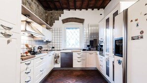 A kitchen with white cabinets, a black dishwasher, and a window with a diamond pattern.