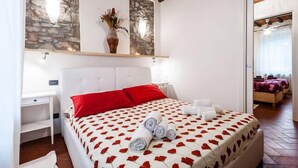 A bedroom with a bed, a nightstand, and a wall-mounted shelf with a vase.