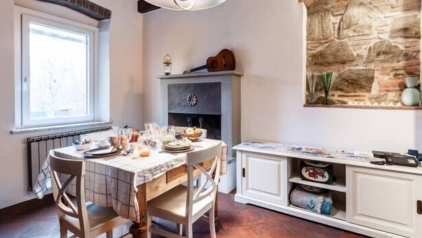 A dining area with a table set for four, a stone wall, and a window providing natural light.