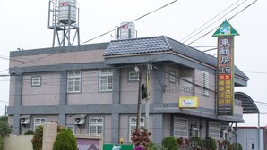 A building with a water tank on top, a signboard with Chinese characters, and several potted plants in front.