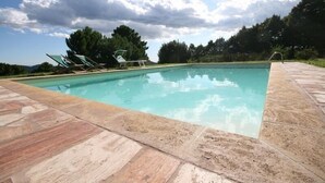 Piscina retangular com espreguiçadeiras e deck revestido.