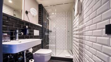 Un baño moderno con ducha acristalada, lavabo blanco y retrete.