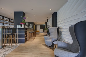A modern lobby with a reception desk, bar stools, and seating area. - Vienna House Easy by Wyndham Dortmund  (Dortmund)