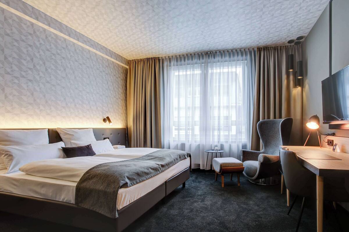 Une chambre d’hôtel avec un grand lit, un bureau avec une chaise, une petite table et un téléviseur.