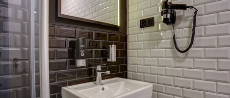 Un baño moderno con un lavamanos blanco, un espejo y un secador de pelo fijado a la pared.