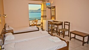 A hotel room with two beds, a desk, chairs, and a TV. - Akrogiali (Kissamos)