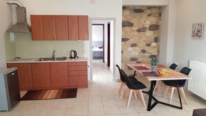 A compact kitchen with wooden cabinets, a built-in oven, and a dining area with a table and chairs. - Akrogiali (Kissamos)