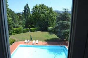 Une vue sur une piscine, avec des chaises longues et une pelouse bien entretenue.
