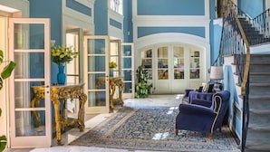 Un'ampia sala d'ingresso con una maestosa scala, arredi eleganti e un grande tappeto decorativo.